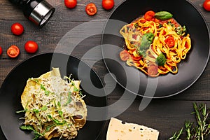 Two plate with pasta top view. alfredo pasta with beef and marinara pasta on wooden table with ingredients, pepper and cheese