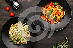 Two plate with pasta top view. alfredo pasta with beef and marinara pasta on wooden table with ingredients, pepper and cheese