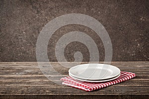 Two plate and red-white checkered napkin on wooden table