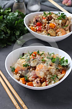 Two plates fried rice with seafood, vegetables, ginger and parsley on dark background. Asian cuisine. Vegetarian food. Vertical