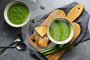 Two plates of homemade green cream asparagus soup, vegetarian and vegan food. Top view