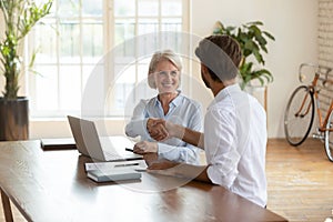 Two pleasant business partners shaking hands, celebrating good deal.