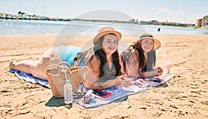 Two plus size overweight sisters twins women relaxing lying on a towel at the beach on summer holidays