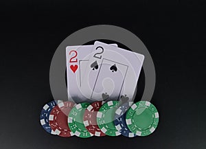 Two poker deuces on black table with chips on black background