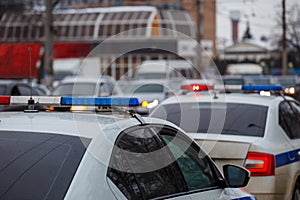 two police cars lights in city street at winter day with cars traffic in blurry background