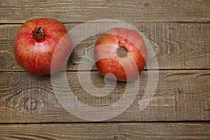 Two pomegranates on a wooden table. Healthy fruits, vegan food, diet. Flat lay. Top view. Copy space.