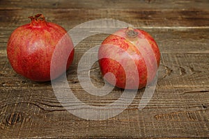 Two pomegranates on a wooden table. Healthy fruits, vegan food, diet. Flat lay. Top view. Copy space.