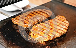 Two pork steaks grilled on electric grill, metal plate