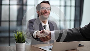 Two positive confident businessmen shaking hands over meeting table after negotiation,