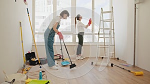 Two positive females cleaning room together. home cleaning services, cleaning ladies mopping floor, vacuuming carpet