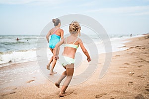 Two positive little girls run along sandy beach