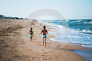 Two positive little girls run along sandy beach