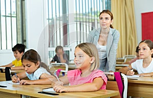 Two positive small school girls sitting together in classroom