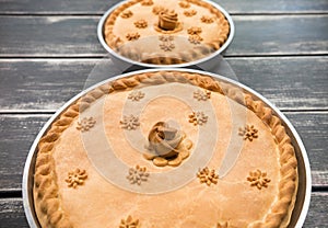 Two potato pies with edible decorations on top standing on the wooden table