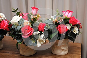 Two pots of artificial flowers on a wooden table