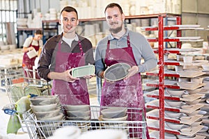 Two potters holding handcrafted ceramic plates in pottery workshop photo