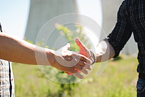 Two power line tower workers with handshaking.