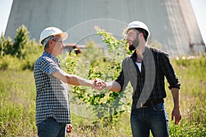 Two power line tower workers with handshaking.