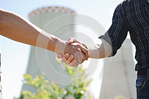 Two power line tower workers with handshaking.