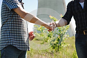 Two power line tower workers with handshaking