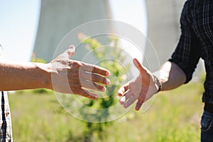 Two power line tower workers with handshaking.