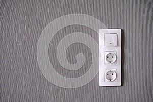 Two power sockets and Light switch on gray wall