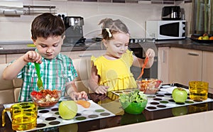 Two preschool children who eat healthy food in the kitchen