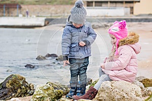 Two preschoolers actively playing on stony beach