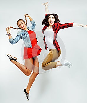 Two pretty brunette and blonde teenage girl friends jumping happy smiling on white background, lifestyle people concept