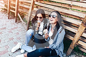 Two long hair brunette girls talking and eating ice cream outdoor