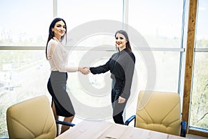 Two pretty Businesswomen shaking hands in modern office