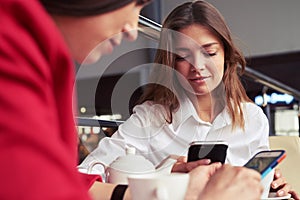 Two pretty busy females working in smartphones and drinking coffee