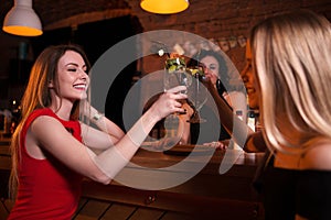 Two pretty Caucasian girls toasting drinking cocktails in pub celebrating birthday