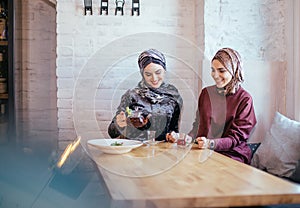 Two caucasian muslim woman drinking tea in cafe