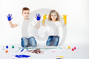 Two pretty child friends boy and girl are drawing pictures by paints. Showing hands in paint, sckream, roar, happy.