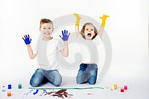 Two pretty child friends boy and girl are drawing pictures by paints. Showing hands in paint, sckream, roar, happy.