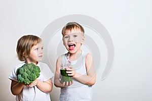 Two pretty fun kids with green smoothies and broccoli. Helthy an