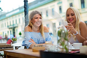 Two pretty girlfriends laughing while sitting in a bar