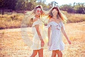 Two pretty girlfriends in summer dresses