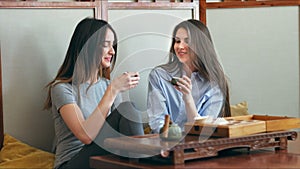 Two pretty girlfriends talk and drink tea in cafe