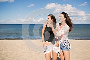 Two pretty girls on beach looking at something laughing