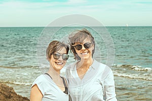 Two pretty girls on the beach smiling and looking at each other