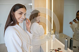 Two pretty girls standing near the mirror and smiling