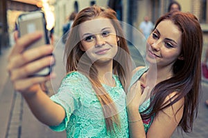 Two pretty girls taking selfie. Urban background. We love selfie