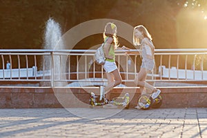 two pretty happy girl riding on hover board or gyroscooter outdoors at sunset in summer. Active life concept