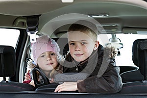 Two pretty little children boy and girl in a car interior