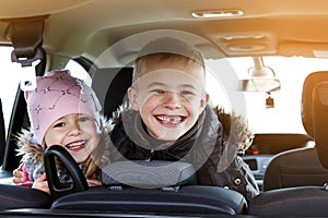 Two pretty little children boy and girl in a car interior, travel concept. Soft light effect