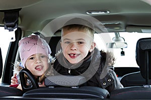 Two pretty little children boy and girl in a car interior