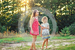 Two pretty little girls embracing and smiling at the countryside. Happy kids outdoors concept