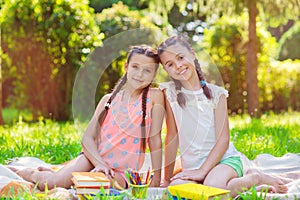 Two pretty little girls reading in park